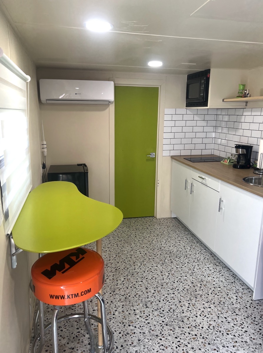 Inside the Rocket Box trailer: a galley kitchen, a lime-green door and an orange KTM bar stool